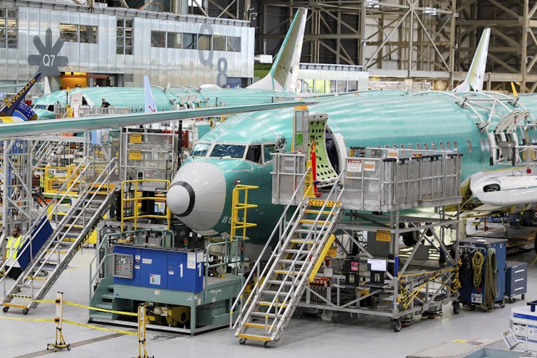 Avions à l’intérieur d’une usine. Des escaliers mènent à la porte d’entrée ouverte de chaque avion.